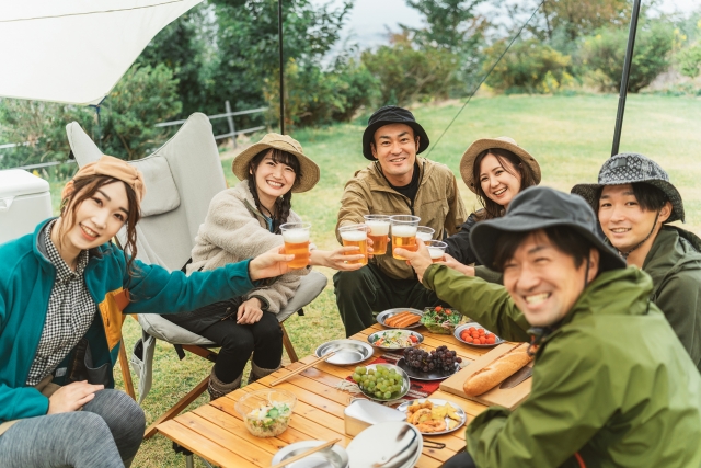 秋冬のキャンプ場で仲間と乾杯する男女