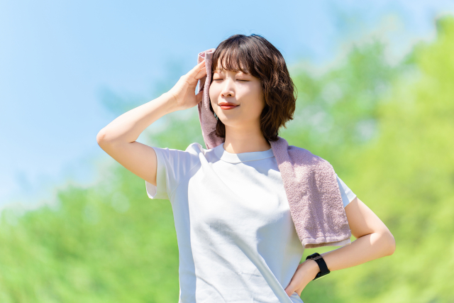 タオルで汗を拭く女性・スポーツ